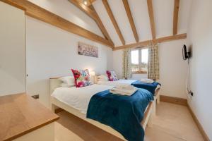 two twin beds in a room with wooden ceilings at The Old Cowshed in Stone