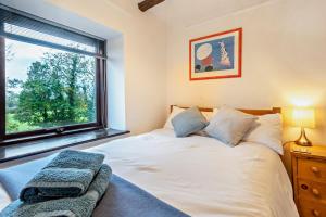 a bedroom with a large white bed and a window at Rosie Cottage in Bassenthwaite