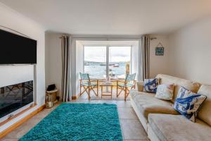 Una sala de estar con un sofá, un televisor y una mesa. en Saltwhistle Beach, en Teignmouth