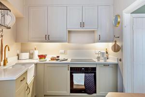 a kitchen with white cabinets and an oven at Trehawn Cottage in Saint Columb Major