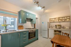 a kitchen with green cabinets and a wooden table at Iona Cottage - Allonby in Allonby