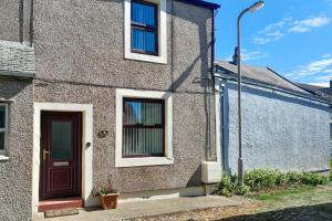 a brick house with a door and a street light at Iona Cottage - Allonby in Allonby