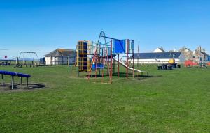 a park with a playground with a slide and swings at Iona Cottage - Allonby in Allonby