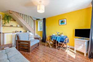 a living room with a couch and a table with a tv at Laurel Cottage - The Retreat in Malvern Wells