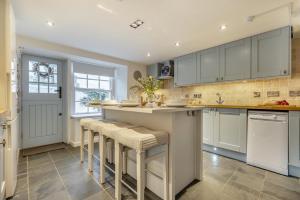a kitchen with white cabinets and bar stools at River Watch - Fowey in Fowey