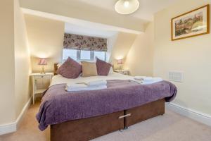 una camera da letto con un letto grande con lenzuola viola di Orchard Cottage a Preesgreen
