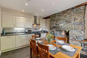 a kitchen with a table with chairs and a stone wall at Parlwr Mawr in Dyffryn