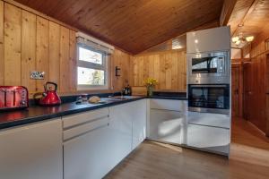 eine Küche mit weißen Geräten und Holzwänden in der Unterkunft Birch Lodge in Thornton Watlass