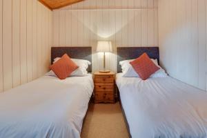 2 Einzelbetten in einem Zimmer mit einer Lampe auf einem Nachttisch in der Unterkunft Birch Lodge in Thornton Watlass
