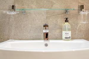a bathroom sink with a bottle of alcohol on it at Harbour Sands - St Ives in St Ives +13 photos