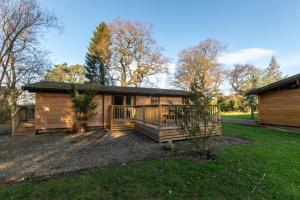 ein Blockhaus mit einer Veranda und einem Haus in der Unterkunft Birch Lodge in Thornton Watlass