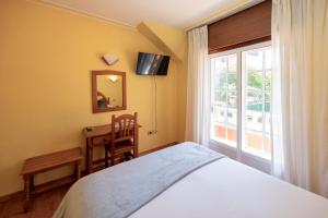 a bedroom with a bed and a window and a mirror at Hotel Restaurante Isape GBC in Arcade
