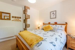 ein Schlafzimmer mit einem großen Bett mit gelber Bettwäsche in der Unterkunft Archway Cottage - Caldbeck in Caldbeck