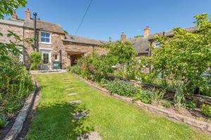 ein altes Steinhaus mit Garten davor in der Unterkunft Archway Cottage - Caldbeck in Caldbeck