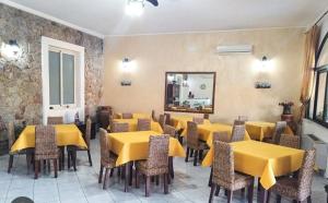 a restaurant with yellow tables and chairs and a mirror at BeB Verdemare in Santa Teresa di Riva