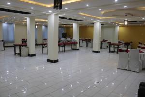 Una gran sala con mesas y sillas en un edificio. en Royal Blue Hotel, en Islamabad