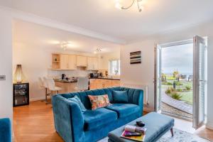 a living room with a blue couch and a kitchen at Fistral Gaze in Newquay