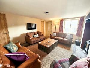 a living room with leather furniture and a coffee table at Low Moor Farm in Cotterdale