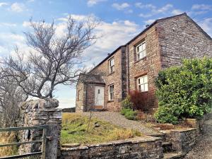 an old brick house with a fence in front of it at Low Moor Farm in Cotterdale