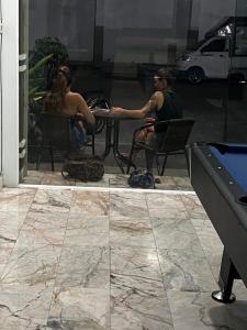 two people sitting at a table on a patio at European Hostel Central Pattaya in Pattaya