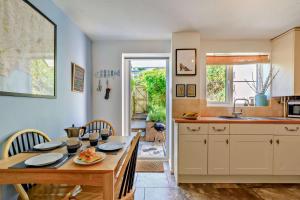 een keuken met een tafel en stoelen en een eetkamer bij Pink Cottage in Beer