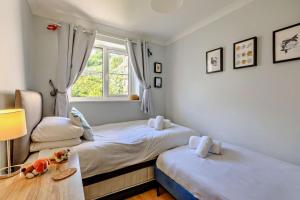 een slaapkamer met twee bedden en een raam bij Pink Cottage in Beer