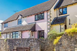 een huis met een stenen muur en een bank bij Pink Cottage in Beer