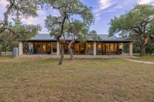 a house with glass doors and a tree at Ultimate Hill Country Retreat, POOL, Creek, Sleeps 10 in Dripping Springs