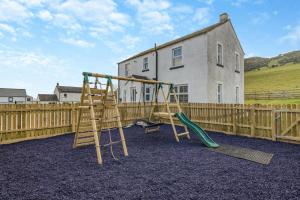 a playground with two swings and a wooden fence at Orchard House - Cockermouth in Embleton