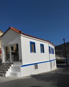 a small white house with blue windows and stairs at Rania's Seaview Corner in Samos