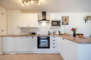 une cuisine avec des armoires blanches et un comptoir dans l'établissement No Road - The Cottage, à Bewdley