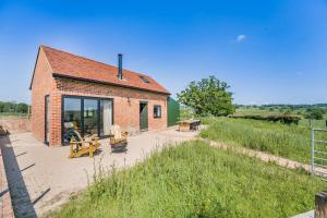 een klein bakstenen huis met een terras in een veld bij Great Knights Cottage in Westfield