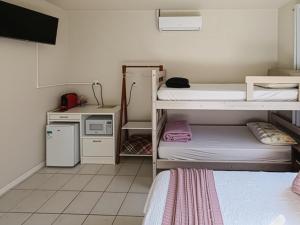 a small room with two bunk beds and a microwave at Quarto Aconchego 345 ao lado Alles Park in Pomerode