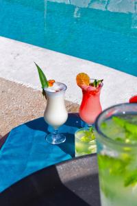 three cocktails sitting on a table next to a pool at Hotel Plaza Palenque in Palenque