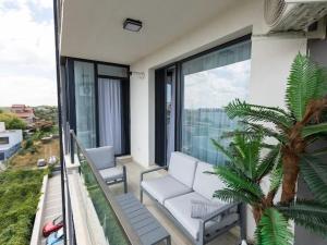 a balcony with a white couch and a palm tree at Apartament Lara mamaia in Mamaia Sat/Năvodari