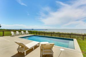a swimming pool with two chairs and a table at Luxury Beachfront Living! Epic Ocean Springs Home in Ocean Springs