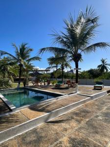 a swimming pool with palm trees in the background at Pousada Bouganvile Atins in Atins +26 photos