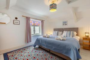 ein Schlafzimmer mit einem Bett mit blauer Bettdecke und einem Fenster in der Unterkunft Shipwrights Cottage - Appledore in Appledore