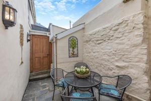 eine Terrasse mit einem Tisch, Stühlen und einer Tür in der Unterkunft Shipwrights Cottage - Appledore in Appledore