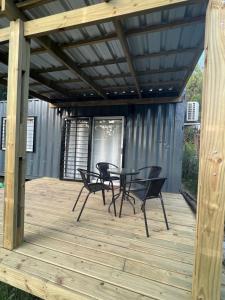 eine Terrasse mit Tisch und Stühlen auf einem Deck in der Unterkunft Casa contenedor VoVo in Barra de Portezuelo