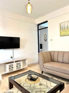 a living room with a couch and a tv at Cozy 1br milimani in Kisumu