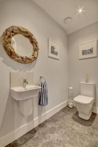 Un baño con inodoro, lavabo y espejo. en Hectors House, en Croyde 27 fotos más