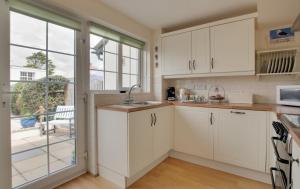 Una cocina con gabinetes blancos y una ventana grande. en Stones Throw, en Instow 15 fotos más