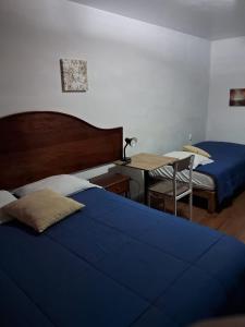 a bedroom with two beds and a table with a desk at Villas Del Sol Bed & Breakfast in Lima
