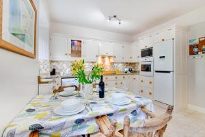 una cocina con mesa y sillas y una cocina con armarios blancos. en Morvah 7 Zodiac House, en Saint Levan 8 fotos más