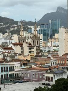 a city with buildings and a city with mountains in the background at Flat Centro Rio Av Presidente Vargas x Uruguaiana - Vista panorâmica do Cristo & Metrô in Rio de Janeiro