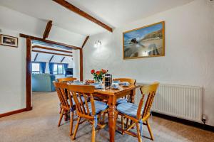 a dining room with a wooden table and chairs at Wagtail Cottage in St Merryn