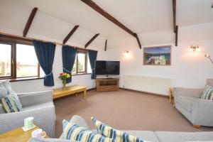 a living room with couches and a flat screen tv at Wagtail Cottage in St Merryn