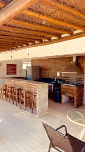 a kitchen with a bar with stools and a stove at Apt 2 quartos com Vista Mar Piscina e Varanda 200 m da Praia Ilheus BA in Ilhéus