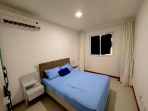 a bedroom with a blue bed and a window at Apt 2 quartos com Vista Mar Piscina e Varanda 200 m da Praia Ilheus BA in Ilhéus
